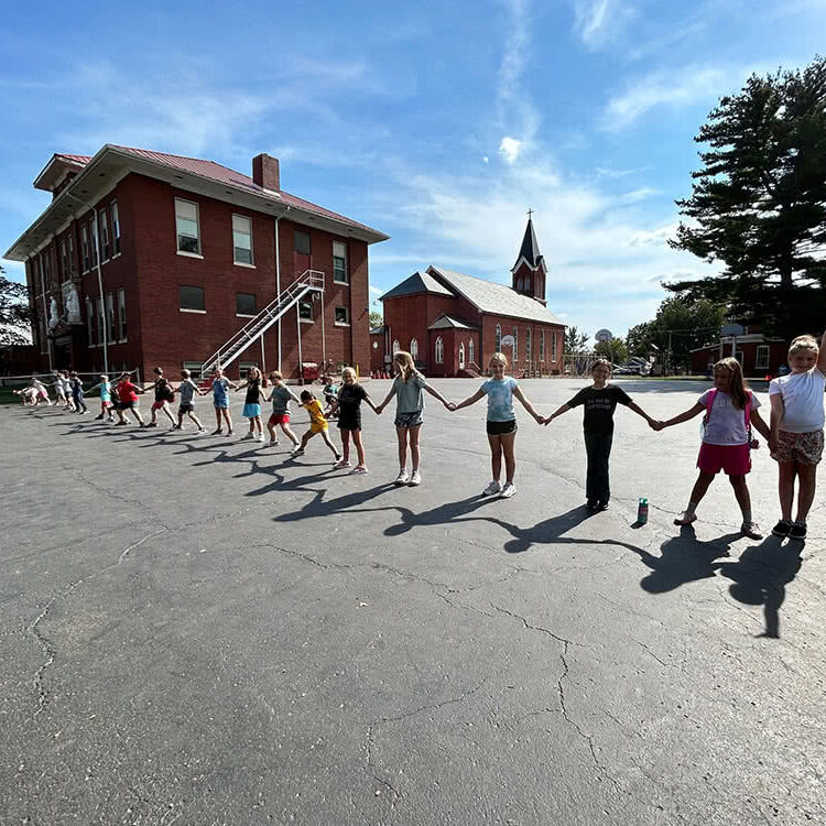 Kids holding hands outside forming a long line